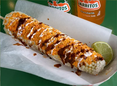 traditional elote loaded with doritos, cheese sour cream and hot sauce
